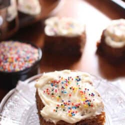 A slice of Frosted Chocolate Chip Cookie Bar with rainbow sprinkles on a small plate