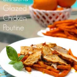 A plate of Honey Sriracha Glazed Chicken Poutine next to a bowl of oranges and a plate of sweet potato fries
