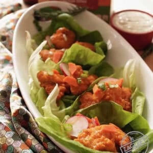 Baked Buffalo Chicken Lettuce Wraps in an oval dish next to a small bowl of ranch