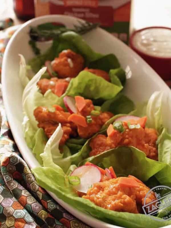Baked Buffalo Chicken Lettuce Wraps in an oval dish next to a small bowl of ranch