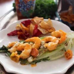 Grilled Buffalo Shrimp on grilled Romaine lettuce topped with blue cheese crumbles plated with chips
