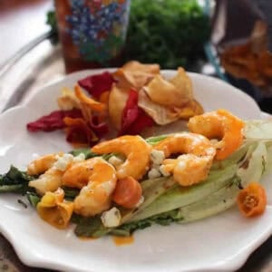 Grilled Buffalo Shrimp on grilled Romaine lettuce topped with blue cheese crumbles plated with chips