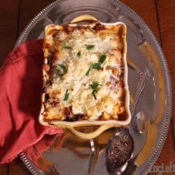 Overhead view of Moussaka in a baking dish on a metal tray with a red cloth napkin.