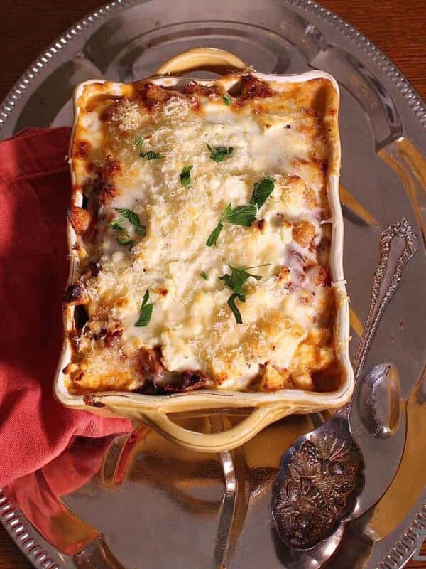 Overhead view of Moussaka in a baking dish on a metal tray with a red cloth napkin.