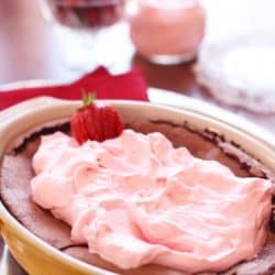 flourless chocolate cake in pan with pink cream topping
